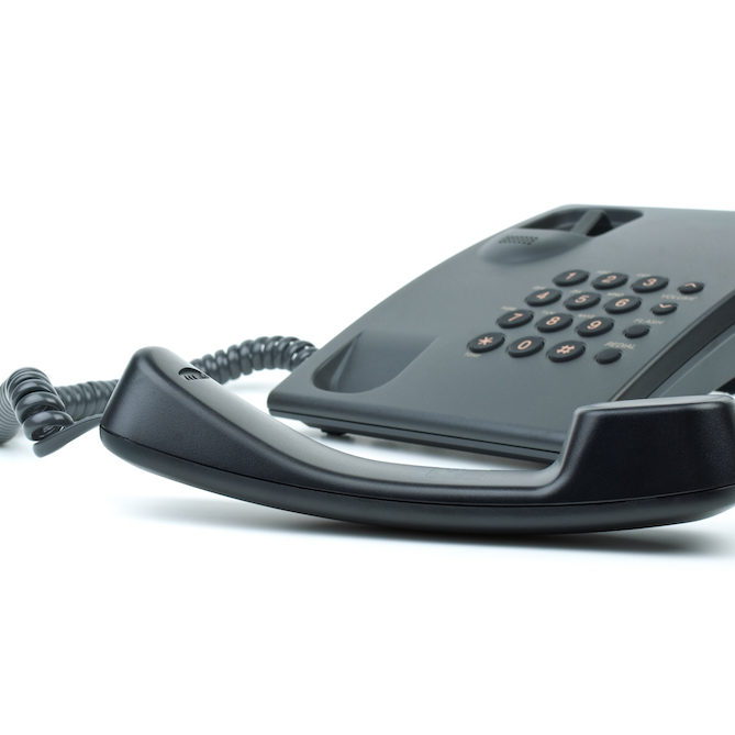 Black office phone with handset in foreground
