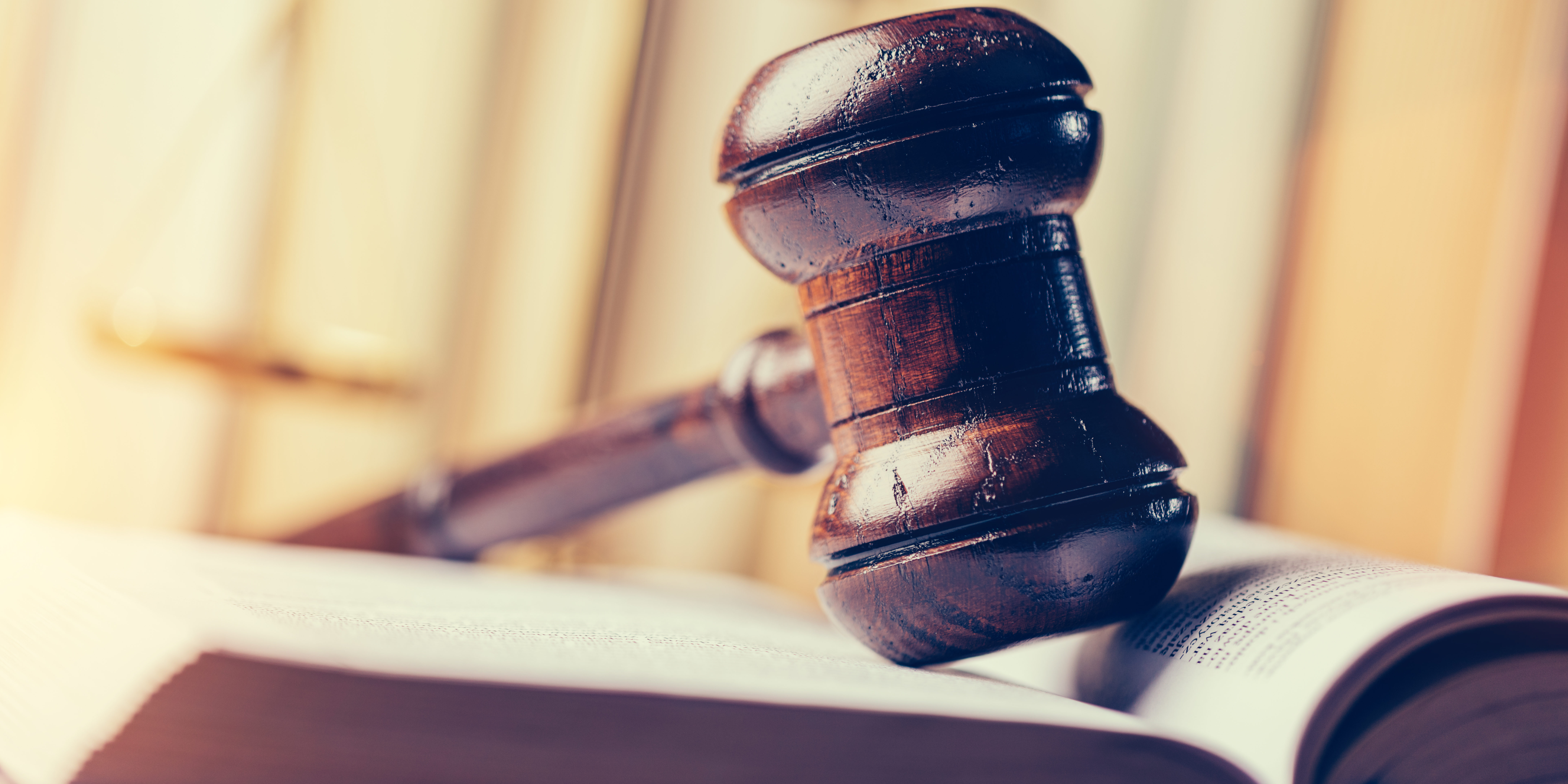 Court hammer laying on book.